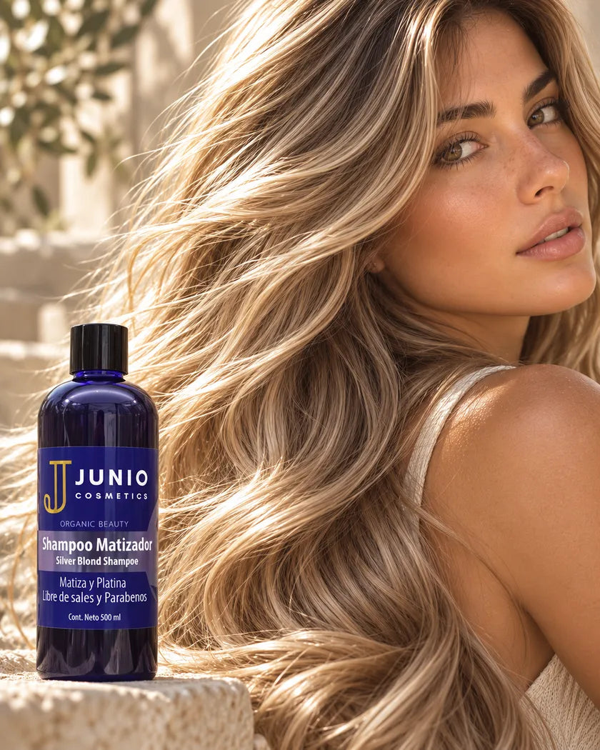Cabello largo rubio, brillante y en movimiento, con el rostro de la modelo a la derecha y un frasco de Shampoo Matizador JUNIO sobre la piedra.